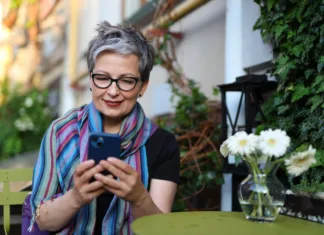 Paket Mobitel Penzion 300 plus s podvojenimi količinami enot za zmeraj A cheerful senior woman using modern technology, her smartphone, for communication and leisure outdoors.