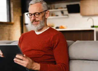 BIBLOS: E-knjige prinašajo veliko prednosti tudi za starejše Closeup portrait of a smiling caucasian middle-aged mature man in glasses using digital tablet for e-learning, paying bills online, e-commerce, remote work, social media online at home