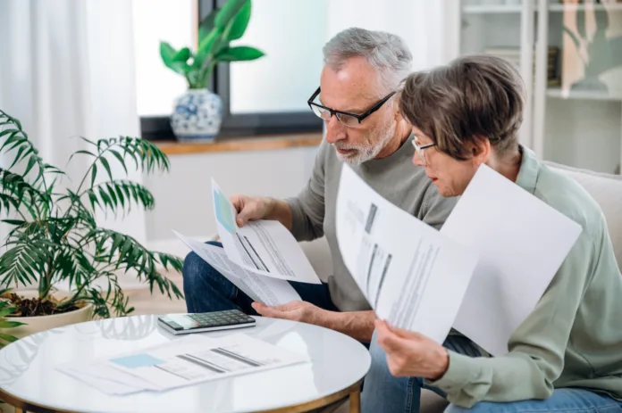 Elderly couple checking documents with tax and internal bills, making payments and discussing budget. Family calculating funds for purchase new home or car.