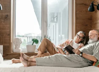 Kakšno ležišče izbrati za zdrav spanec in boljše počutje Elderly man lying on bed reading a book beside an elderly woman