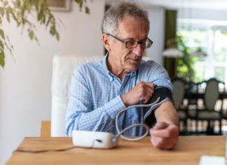 Samomerjenje krvnega tlaka zagotavlja varnost Senior man using medical device to measure blood pressure