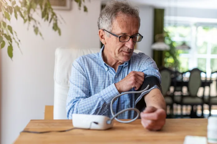 Senior man using medical device to measure blood pressure