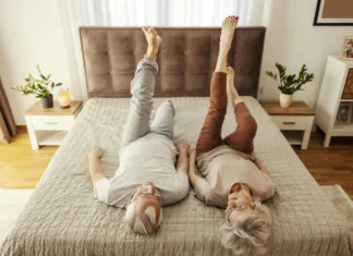 5 preprostih vaj, ki bi jih morali izvajati vsako jutro A senior couple is lying on a bed at home and doing morning gymnastic.