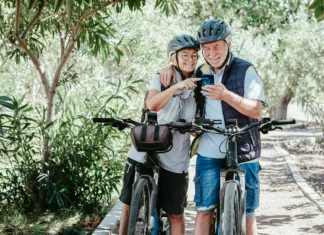 So električna kolesa primerna za starejše? Prednosti in slabosti Active senior caucasian couple with electro bikes looking at smart phone outdoors in the park. Two happy elderly people enjoying nature and healthy lifestyle