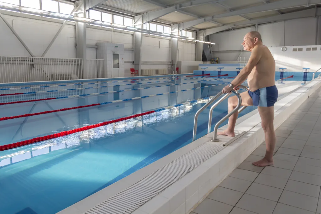 An elderly man is actively engaged in swimming and sports in the pool in a retired sports complex