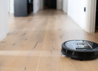 Robotski sesalniki za starejše: Prednosti in koristi Blurred background of interior apartment with a robot vacuum cleaner that moves independently on a house with wooden parquet. Background neutral for modern apartment