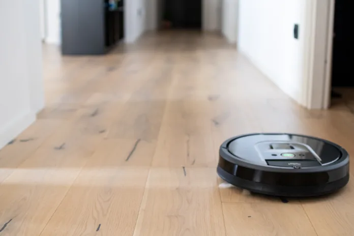 Blurred background of interior apartment with a robot vacuum cleaner that moves independently on a house with wooden parquet. Background neutral for modern apartment