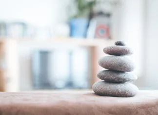 Zakaj opremiti dom po feng šuju Feng Shui: Stone cairn in the foreground, blurry living room in the background. Balance and relaxation.