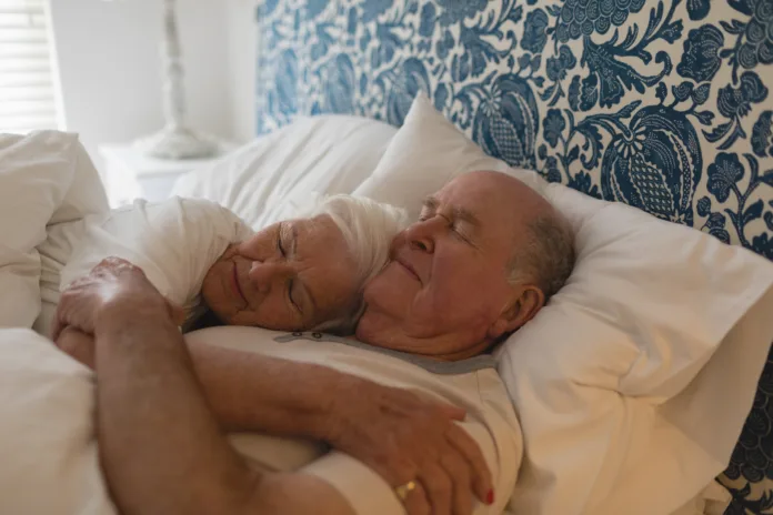 Senior couple embracing together while sleeping in bedroom