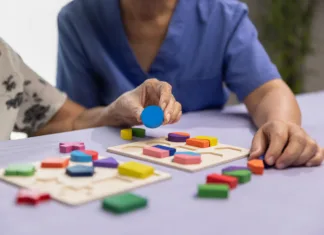 Demenca: dejavniki tveganja in 10 preprostih napotkov za zmanjšanje tveganja Caregiver and senior woman playing wooden shape puzzles game for dementia prevention