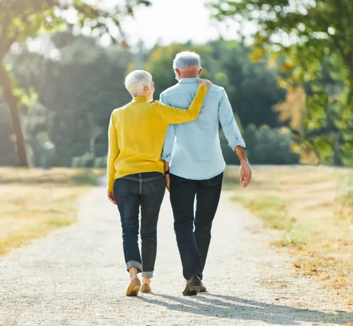 Happy active senior couple walking and holding hands outdoors