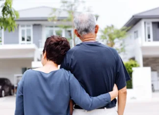 Ali bi moral starejši par prodati veliko hišo in kupiti manjšo nepremičnino? Happy senior couple from behind looking at front of house and car