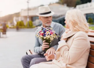 5 stvari, ki jih moški ne želijo slišati na prvem zmenku Two pensioners are sitting on a bench in the alley. An elderly man gives a woman flowers. She is delighted with the gift