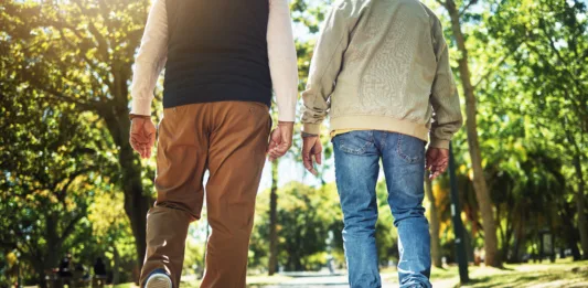 Walking, park and back of men outdoors for wellness, fresh air and health in retirement. Friends, fitness and legs of people on path in nature to relax for training, exercise and cardio workout