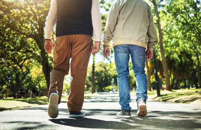 Walking, park and back of men outdoors for wellness, fresh air and health in retirement. Friends, fitness and legs of people on path in nature to relax for training, exercise and cardio workout