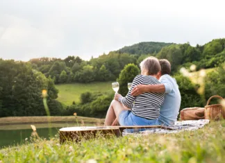 Kam na zmenek? 5 idej za prijetno preživljanje časa v Sloveniji Beautiful senior couple at the lake having a picnic. Green sunny summer nature.