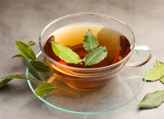Sestavina, ki jo imate zagotovo doma, vam lahko olajša prehlad in kašelj Cup of freshly brewed tea with bay leaves on grey table, closeup