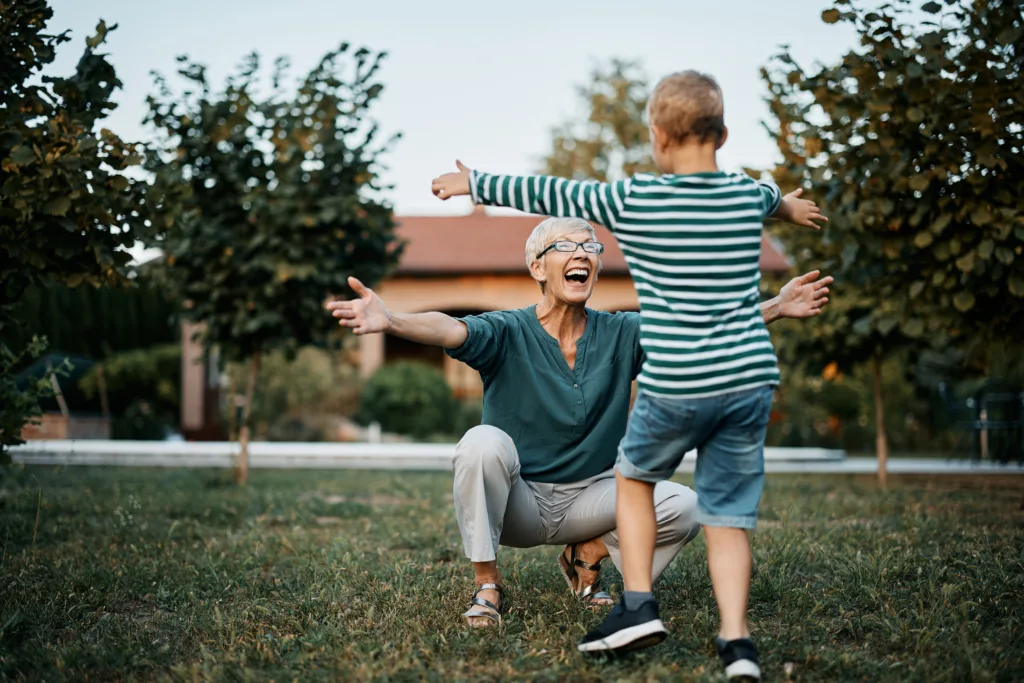 Happy senior woman greeting her son with arms outstretched in the backyard. Copy space.