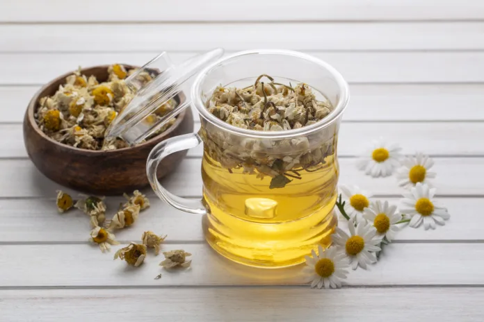 Cup of herbal chamomile tea and daisy flowers.