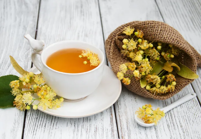 cup of herbal tea with linden flowers on a old wooden background