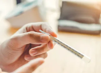 Naravni načini za zniževanje povišane telesne temperature Doctor holding on thermometer for checking sick patient Health care hospital and medicine concept