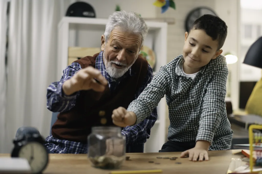 Grandpa and grandson saving money. Grandfather teaching grandchild how to save money.