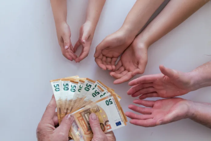 Old grandfather or grandmother hands giving 50 euros banknotes to another pairs of hands of his her wife man and grandchildren kids