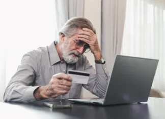 Vse več spletnih nakupov v Sloveniji: Kaj to pomeni za starejšo populacijo? Upset senior elderly man holding credit card by laptop having trouble worry finance safety data or online payment security. Bank client concerned about problem with credit card, financial fraud threat