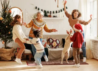 Decembrska evforija je lahko velik stres: Kako obvladati finance Happy positive multiracial family with three kids and golden retriever have fun on Christmas day at home. Mother, grandmother and multiethnic children dance to New Year music during winter holidays