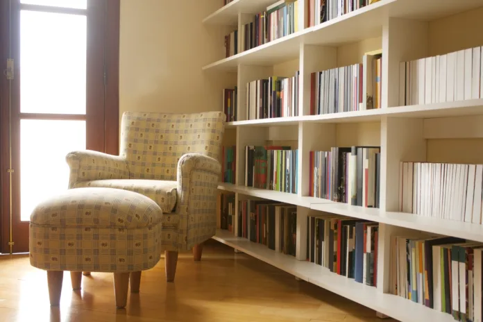 Home library with arm chair. Clean and modern decoration. Natural light coming from window.