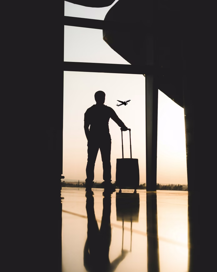 silhouette-of-man-holding-luggage-inside-airport-stockpack-unsplash potovanje silhueta moškega