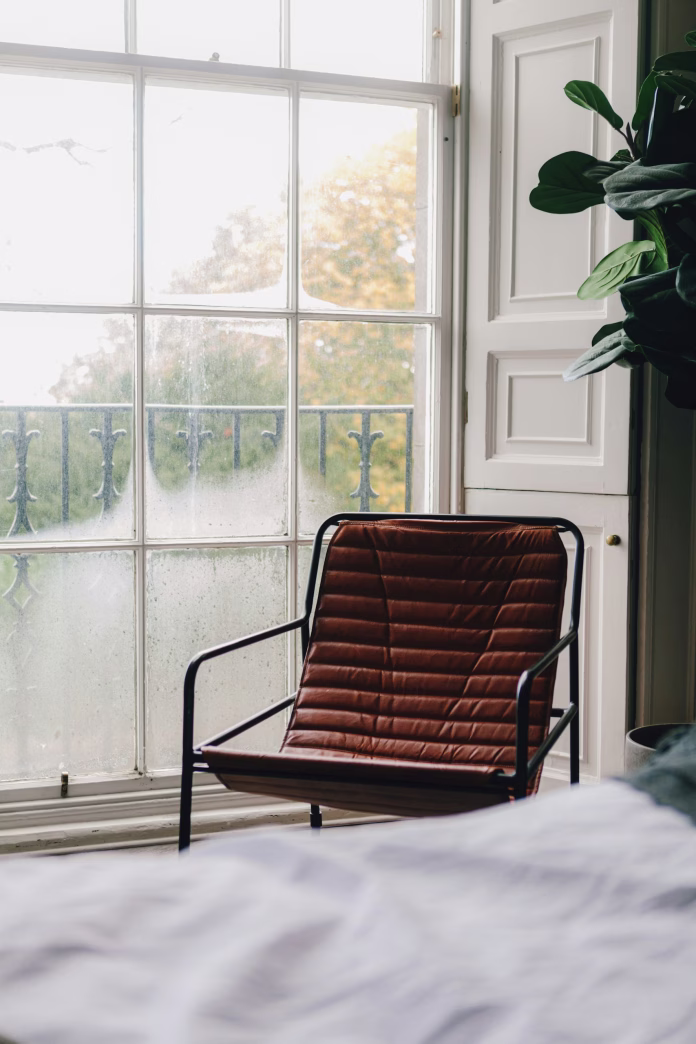 a-chair-sitting-in-front-of-a-window-next-to-a-plant-stockpack-unsplash
