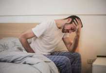 Prepoznajte prve simptome težav s prostato Young man in sleepwear suffering from headache in morning