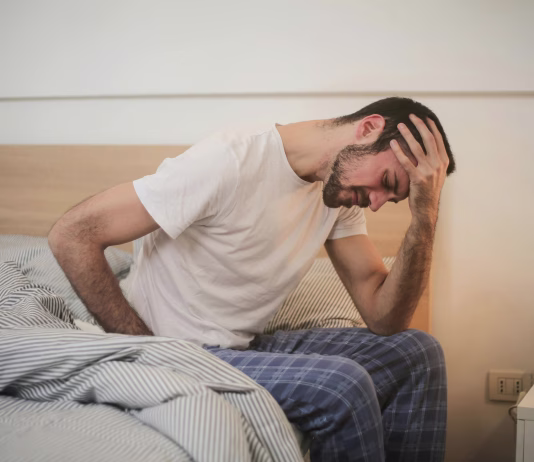 Prepoznajte prve simptome težav s prostato Young man in sleepwear suffering from headache in morning