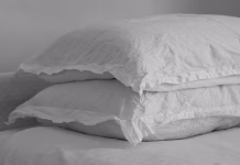 Kako pogosto bi morali prati vzglavnike in zakaj Black and white image of wrinkled linen pillow on a bed.