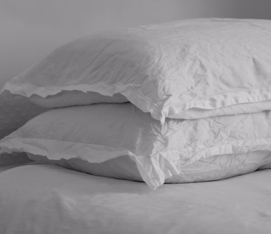 Kako pogosto bi morali prati vzglavnike in zakaj Black and white image of wrinkled linen pillow on a bed.