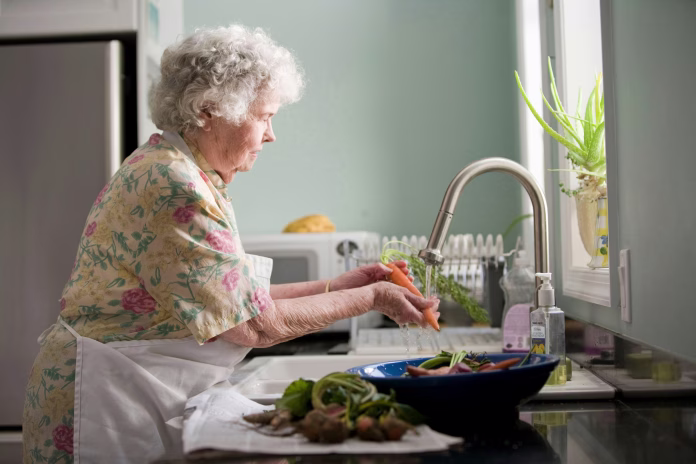 Properly cleaning fresh, uncooked produce is a must when preparing a meal, and with this in mind, the elderly woman pictured here was doing just that, as she was thoroughly cleaning a number of carrots and radishes. Note that there was soil still clinging to the tubers, which would have to be entirely removed using vigorous scrubbing with soapy warm water. Cleaning also will remove environmental pollutants, such pesticides from the foods’ surfaces.