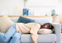 Kdo so energijski vampirji in kako ravnati z njimi Asian woman resting at home on couch, feeling exhausted after work, lacking energy, or overworked, too tired, and lacking motivation