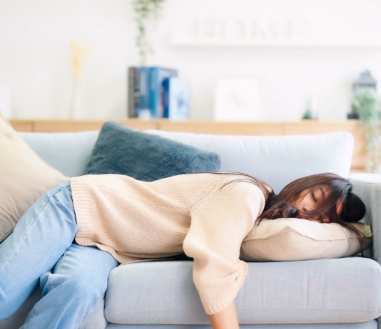 Kdo so energijski vampirji in kako ravnati z njimi Asian woman resting at home on couch, feeling exhausted after work, lacking energy, or overworked, too tired, and lacking motivation