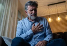 Srčni infarkt: znaki, ki jih ne smete spregledati, in kako ukrepati Mature man having a chest pain while sitting in living room at home.