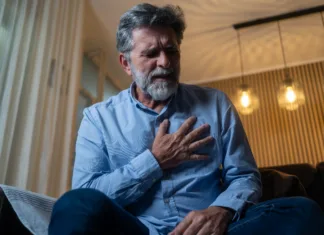 Srčni infarkt: znaki, ki jih ne smete spregledati, in kako ukrepati Mature man having a chest pain while sitting in living room at home.