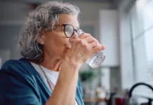 Znaki dehidracije pri starejših: opozorilni simptomi, ki jih poleti ne smete spregledati Mature woman drinking water from a glass at home.