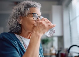 Znaki dehidracije pri starejših: opozorilni simptomi, ki jih poleti ne smete spregledati Mature woman drinking water from a glass at home.