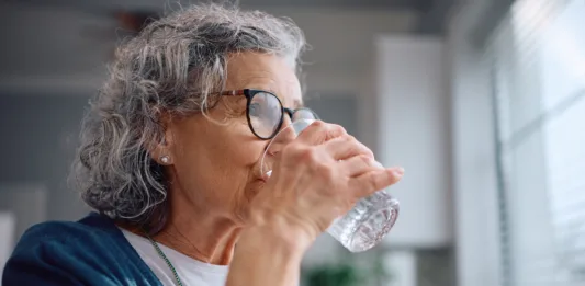 Mature woman drinking water from a glass at home.