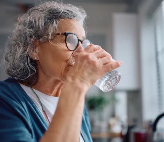 Znaki dehidracije pri starejših: opozorilni simptomi, ki jih poleti ne smete spregledati Mature woman drinking water from a glass at home.