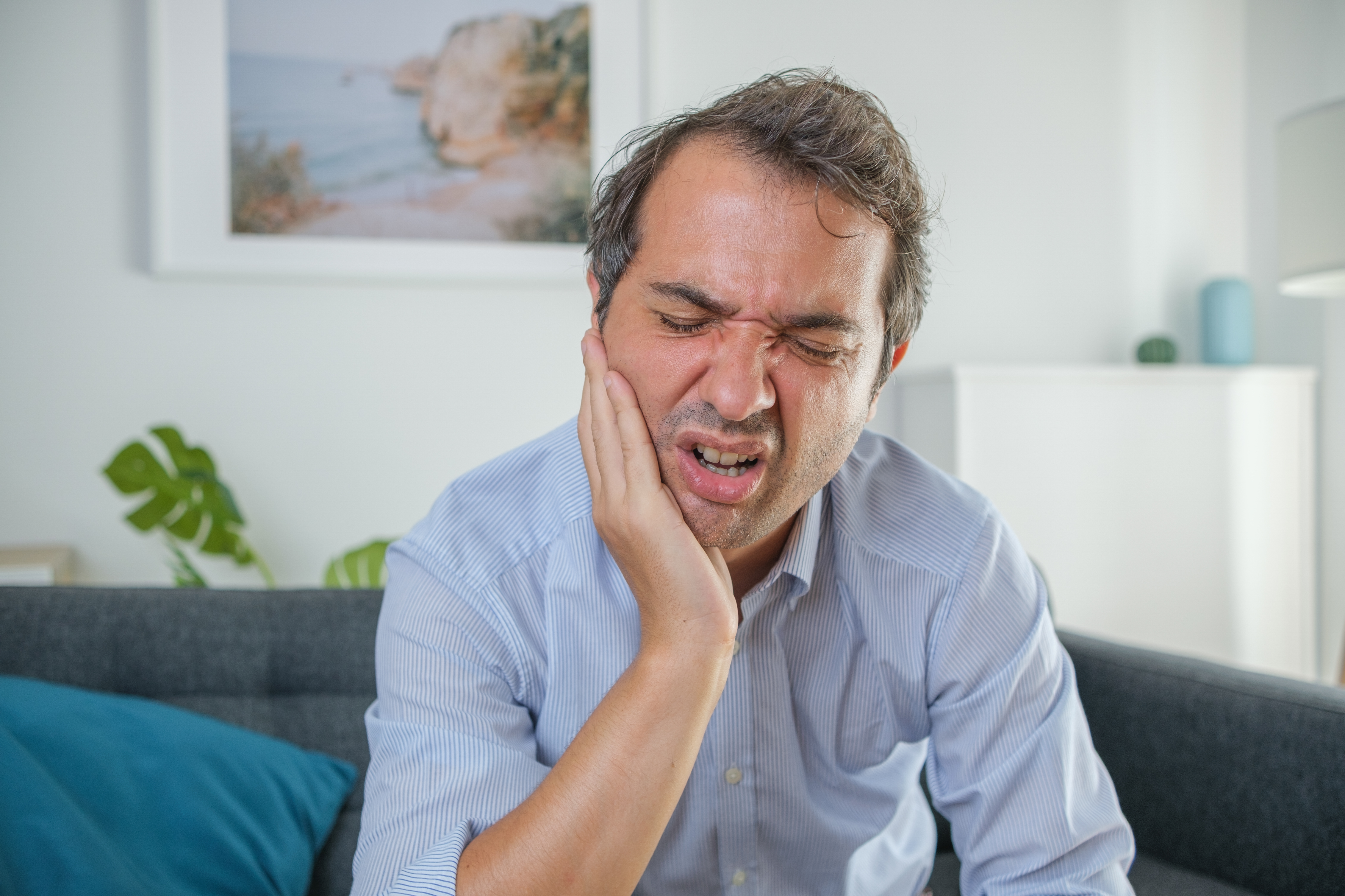 one-man-suffering-toothache-sitting-at-home-stockpack-istock One man suffering toothache sitting at home
