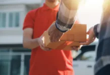 Od julija vas bodo pošiljke s Kitajske lahko pošteno udarile po žepu: Na vsak izdelek 3 evre carine Asian delivery express courier young man use giving boxes to woman customer he wearing protective face mask at front home