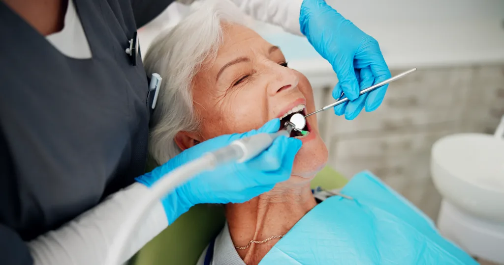 Cleaning, brush and senior woman at dentist for teeth whitening treatment, dentures or oral hygiene. Healthcare, chair and elderly patient in clinic for polish, dental care or plaque with tools