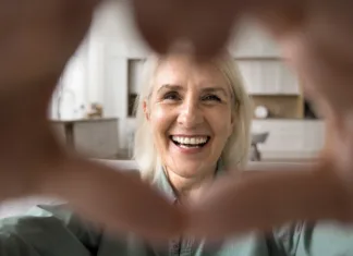 Huda vročina: pogostejši klici in obiski starejših lahko preprečijo resne težave Close up face happy older woman look at camera forming heart shape with her hands, expressing love and connection through video call, highlighting warmth and affection, share tenderness and gratitude
