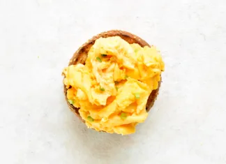 Večina ljudi vse življenje pripravlja umešana jajca narobe. Ta preprost trik naredi veliko razliko Diet scrambled eggs on toasted brioche bun on light background. Tasty meal for breakfast or brunch. Top view, flat lay